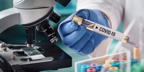 COVID-19 vial with a microscope in the background